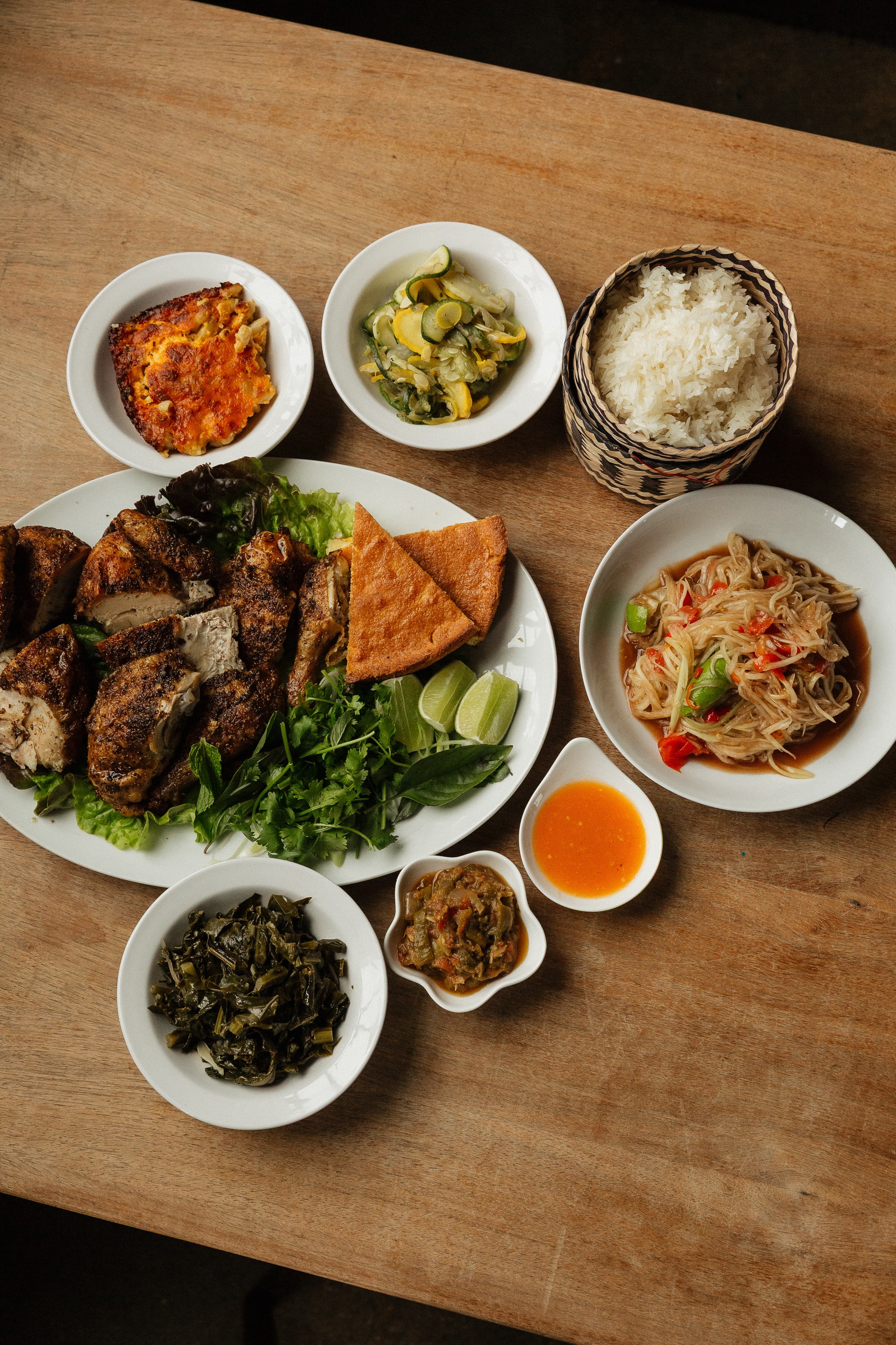 The full Saap Saap BBQ spread — smoked chicken, papaya salad, collard greens, sticky rice and sides